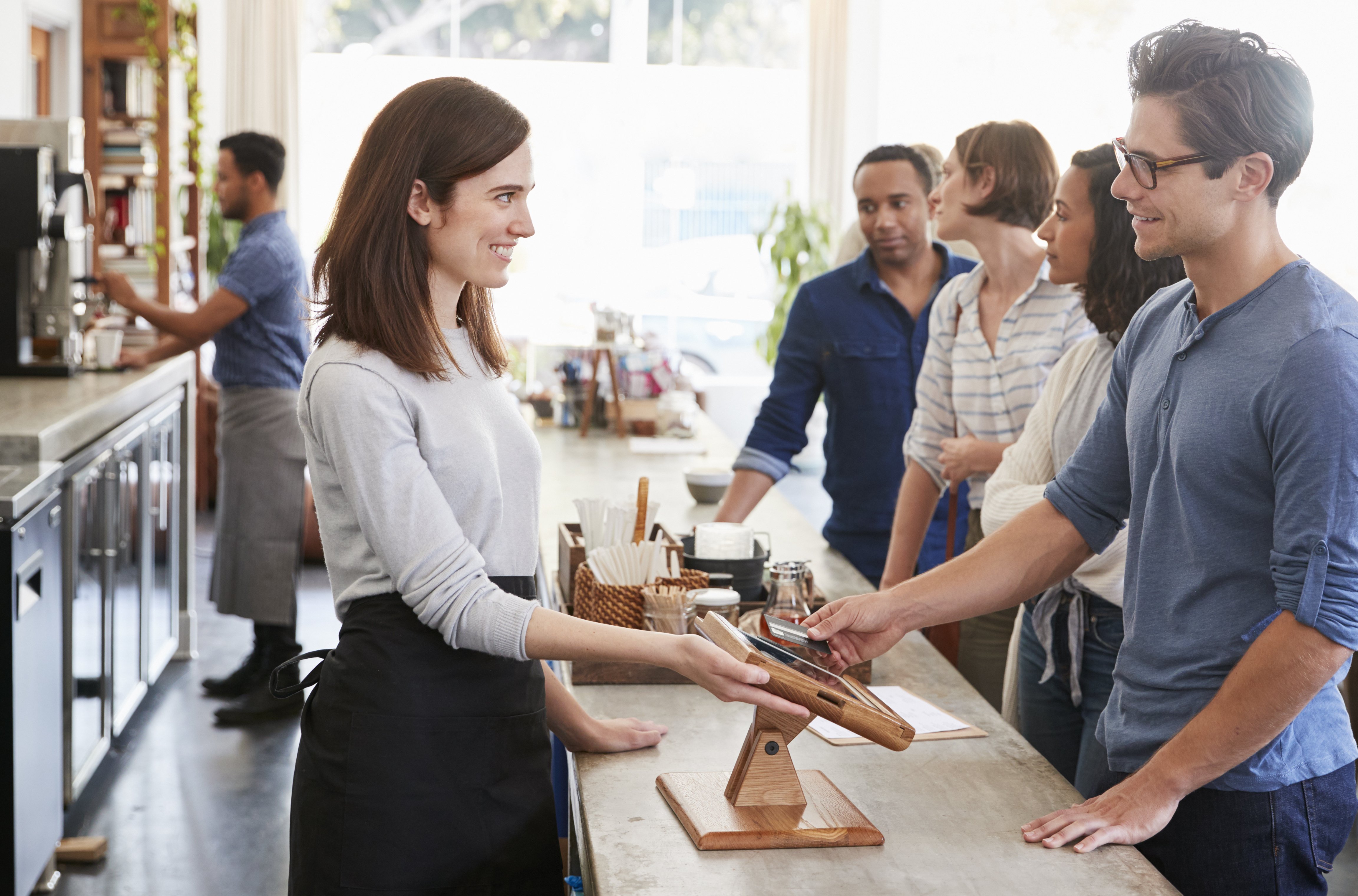 Woman handing payment terminal to customer